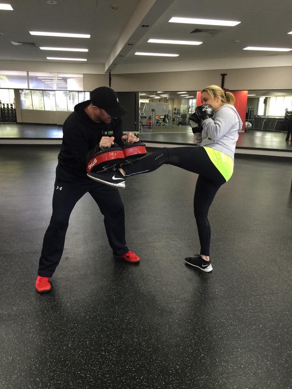 George holding kick pads for a client during a session