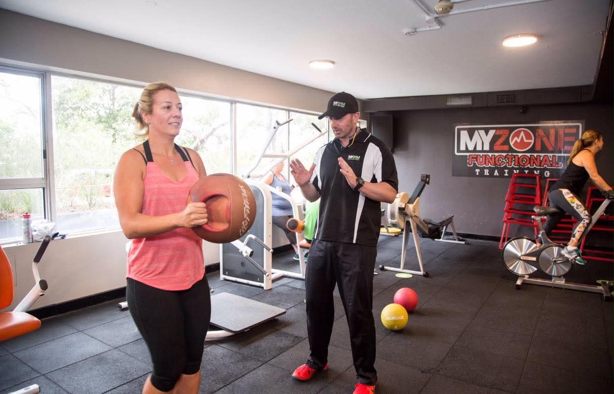 George coaching a client through a medicine ball exercise at MyGym